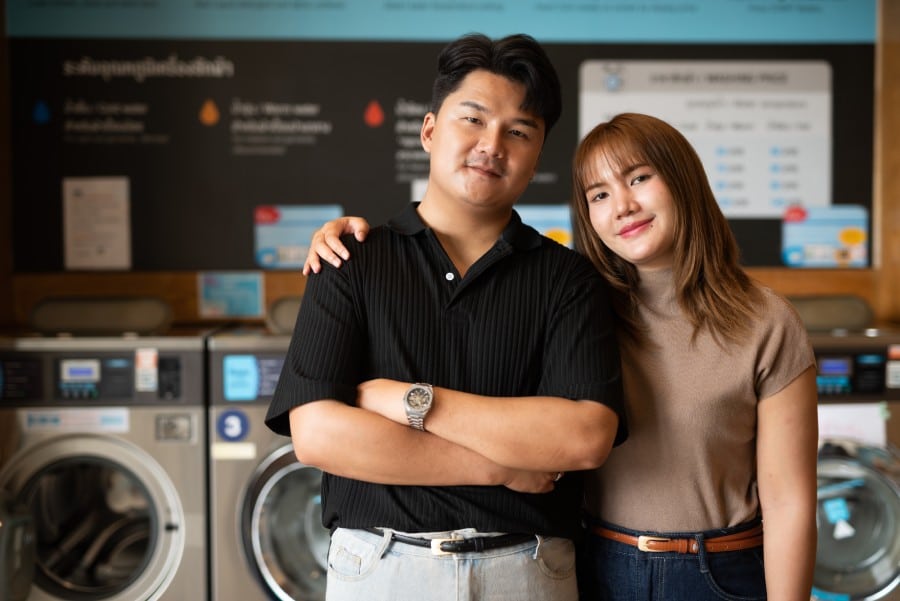 A young asian couple inside a laundry shop.