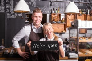 Coffee shop owners showing open sign.