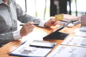 young woman holding credit card and using a laptop computer Businesswoman working at a coffee shop, online shopping, ecommerce, internet banking, spending money, finance, work from home concept.