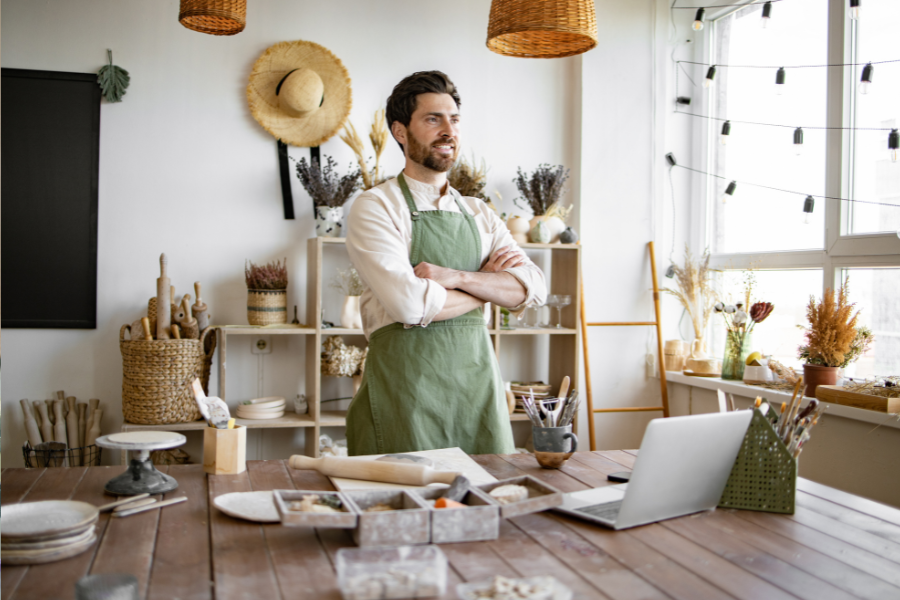 Portrait of male potter, standing in front of table with tools for sculpture.