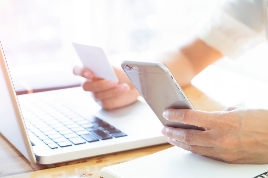 woman using a phone and card to bank online
