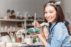 A happy lady painting handcrafted bowls.