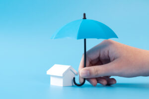 A miniature house protected by a blue umbrella.