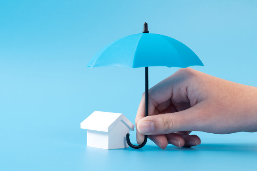 A miniature house protected by a blue umbrella.
