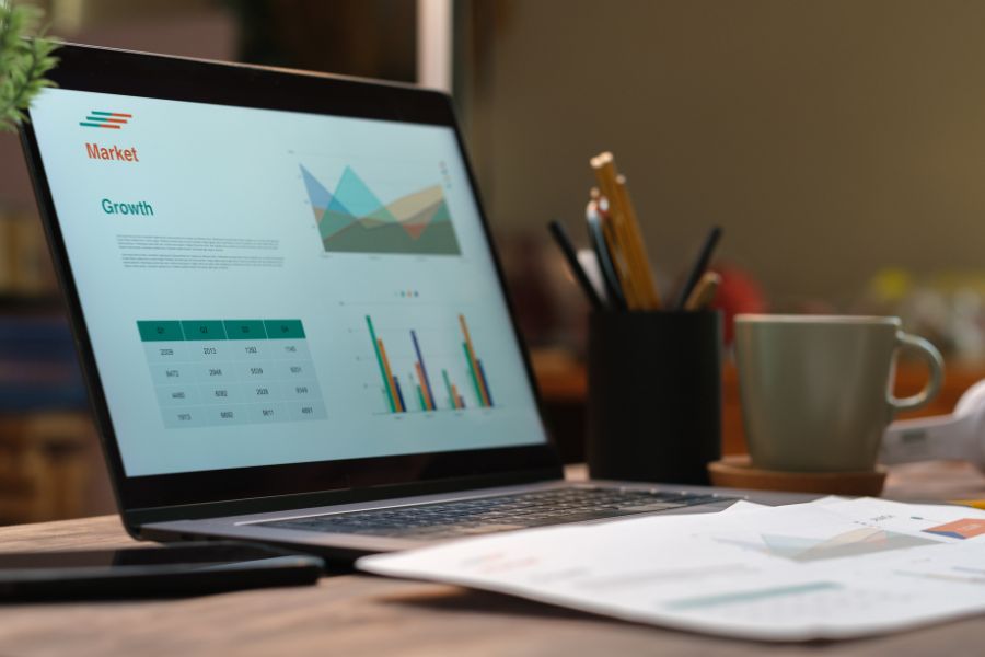 laptop on a table with graphs and charts on screen.