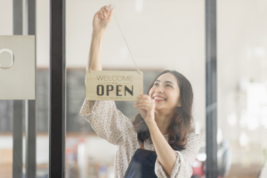 Portrait of happy waitress standing at restaurant entrance.
