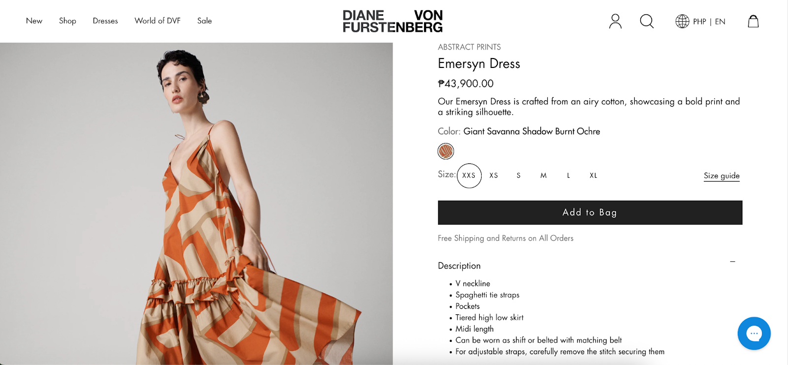 Product page on the Diane von Furstenberg website featuring the Emersyn Dress priced at ₱43,900.00. The dress has a bold abstract print in burnt ochre tones, with a V neckline, spaghetti straps, and tiered high-low skirt. Size options from XXS to XL are shown along with an 'Add to Bag' button. Product description highlights include pockets and styling flexibility.