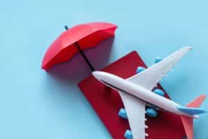 Concept of travel insurance with a miniature airplane and a red umbrella.