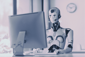 A humanoid AI virtual receptionist wearing a headset sitting at an office computer, representing automated customer service and front-desk digital assistants.