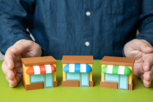 Hand-cupped toy storefronts representing financial support and alternative lending options for small businesses.